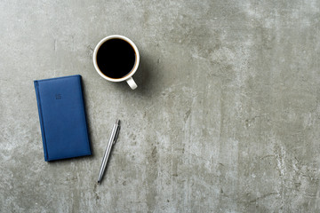 Office desktop with pen, cup of coffee and notebook
