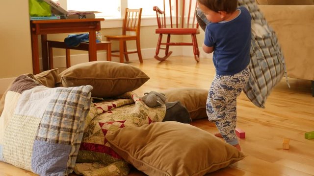 Boy Building A Pillow And Blanket Fort On The Ground