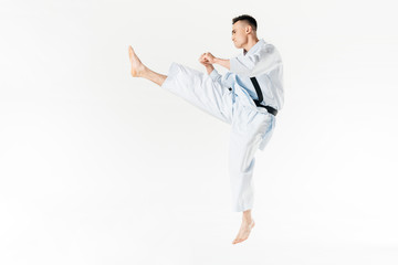 Side view of male karate fighter training isolated on white