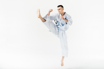 Male karate fighter performing kick isolated on white