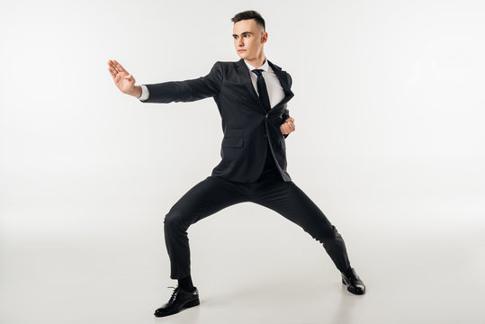 businessman standing in karate position in suit isolated on white - Powered by Adobe