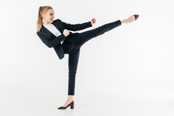 businesswoman performing karate kick in suit and high heels isolated on white © LIGHTFIELD STUDIOS