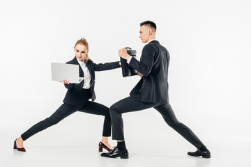 businesswoman holding laptop and kicking businessman in bag isolated on white