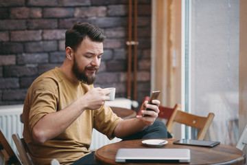 Young man sitting in cafe and using smart phone.