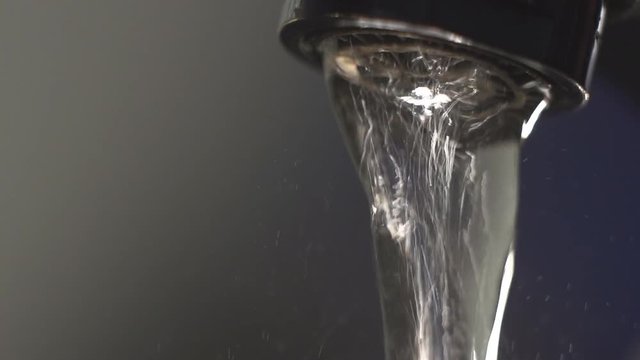 Water flows from the kitchen faucet. Macro. Slow motionWater flows from the kitchen faucet. Macro. Slow motion