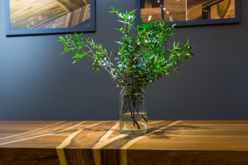 Modern wooden table made of different kinds of wood with a vase with green branches in it