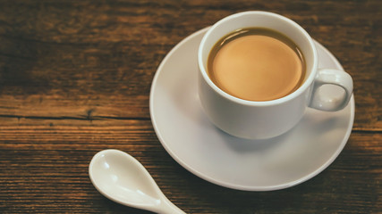 Coffee with milk in a white cup on a wooden background