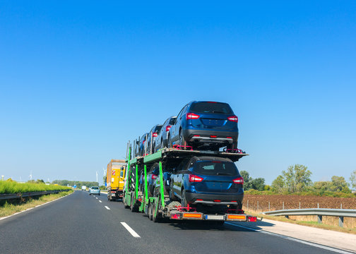 Car carrier trailer with cars on bunk platform. Car transport truck on the highway. Space for text