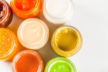 Variety of homemade baby vegetable and fruit puree,  white marble background copy space top view