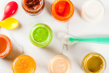 Variety of homemade baby vegetable and fruit puree,  white marble background copy space top view