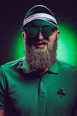 portrait of bearded young man in green polo shirt with shamrock symbol