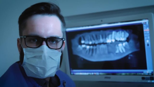 the dentist is studying the x-ray 3D image of the jaw. turns, looks at the camera
