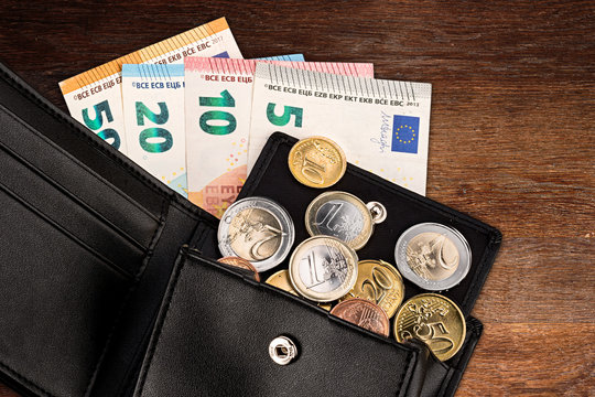 euro coin and bank note in black leather wallet on wood wooden business finance background 
