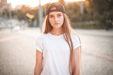 Woman with white shirt and baseball cap walking in city. Shallow depth of field