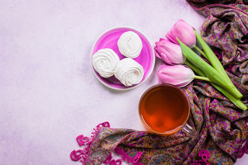 Obraz na płótnie Canvas A bouquet of pink tulips and a cup of tea with homemade marshmallows on wooden tray on stone background table. The Valentine's Day concept, Mother's Day, Wedding. Top view, copy space