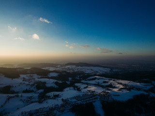 aerial view of beautiful snow-covered trees and houses at sunrise, Germany