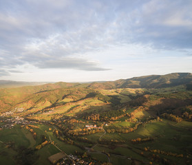 Fototapeta na wymiar aerial view of beautiful green hills with trees and buildings at sunlight, Germany