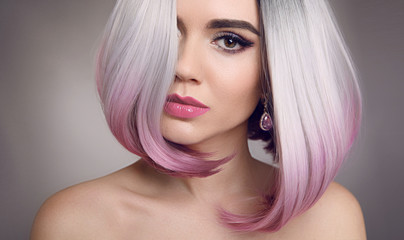 Colored Ombre bob hair extensions. Beauty Blonde Model Girl with short pink hairstyle isolated on gray background. Closeup woman portrait.