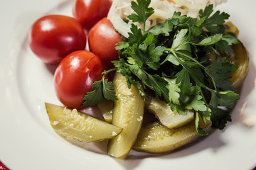Marinated homemade pickled cucumbers and tomatoes on a plate with onions