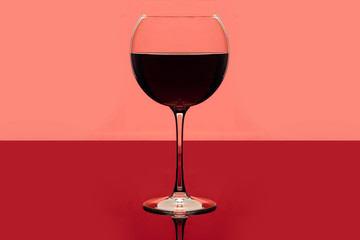 Red wine. Drink glass of red wine on a pink and red background. Alcoholic beverage. Romantic evening or loneliness. Delicious drink with grapes, wine glass