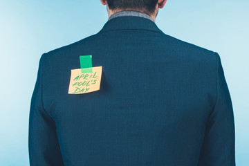 back view of businessman in suit with note with april fools day lettering on back, april fools day concept