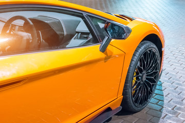 Front wing and the wheel of the car are a supercar, at night in a parking lot in the city.
