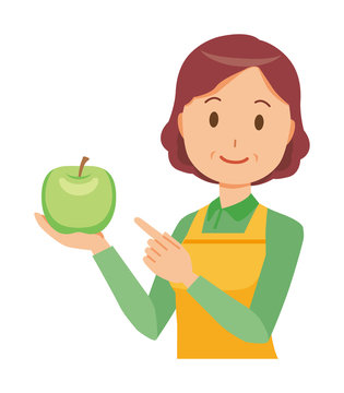 A middle-aged housewife wearing an apron has a green apple
