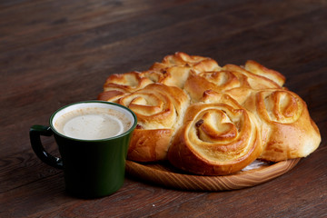 Homemade rose bread on wooden tray with cup of coffee on vintage background, close-up, selective focus
