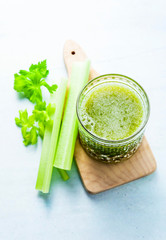 Freshly squeezed celery juice in a glass on a wooden small board on the table. concept and recipe for a healthy diet