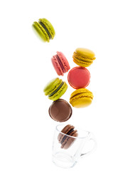 colorful traditional French sweets macaroons from almond flour isolated on white. and an empty glass coffee cup. objects in motion