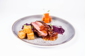 Roast duck breast, red cabbage with apple, roasted potatoes,mountain ash and honey sauce on a white background