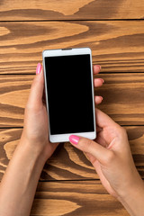 Woman holding smart phone over wooden table. Close up