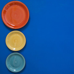 Still life - red, turquoise and yellow dishes on the edge of a blue background