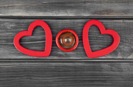 red hearts and condom on a wooden background