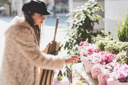 Stylish young woman buying flowers in the city