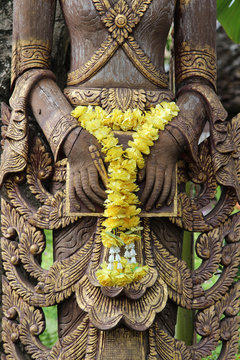 Hand of deva wood carving with yellow flower garland.
