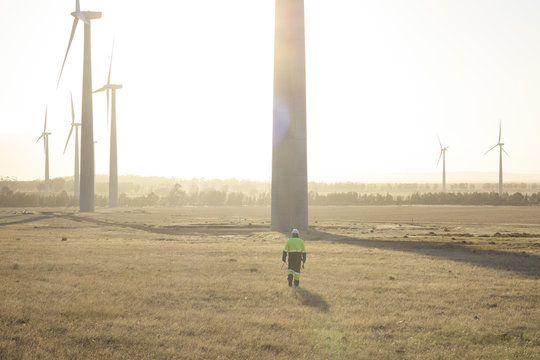 Engineer walking on a wind farm at sunset