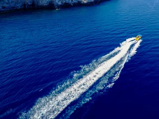Selbstklebende Fototapeten Vogelperspektive des Motorboots, das auf dem exotischen Meer nahe der Küste segelt. © dusanpetkovic1