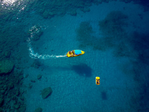 Bird's eyes view of speed and paddle boat on the turquoise coral sea.