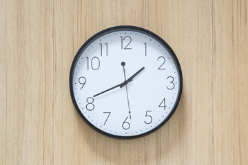 black and white clock hangs on wooden wall