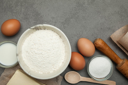 Variety of ingredients for baking on grey background.