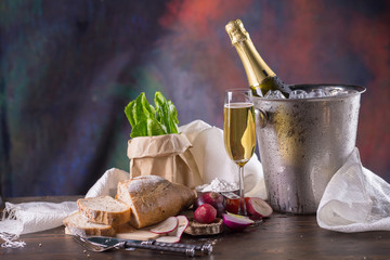 Champagne bottle in bucket with ice and glasses of champagne on dark background