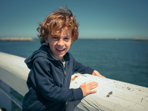 Cheerful boy at handrail at seaside