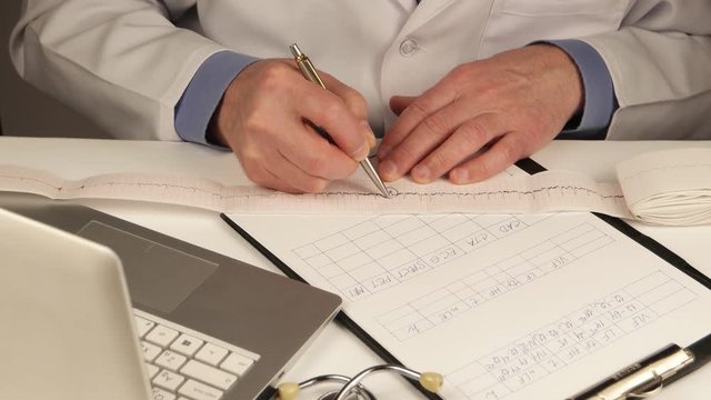 Doctor cardiologist studies clinical record and makes notes in a laptop