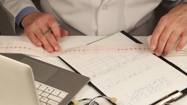 Doctor cardiologist studies clinical record and makes notes in a form