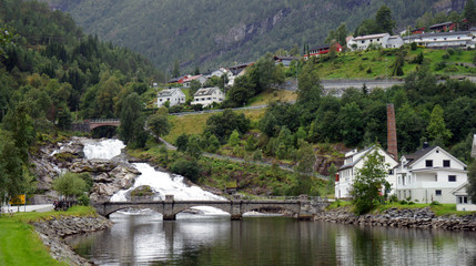 Fototapeta na wymiar Scenic view of waterfall and bridge in Hellesylt, small town at the entrance to Geirangerfjord on a summer day, mountain in the background, More og Romsdal, Norway