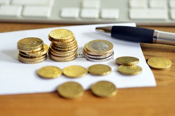 Finance concept Euro coins on a table with computer and pen