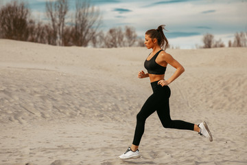 Fototapeta na wymiar Young woman jogging on sand