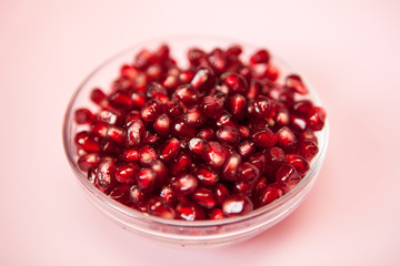 Red pomegranate in bowl on pink background