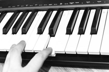 The human fingers press the piano key. Black and white photo.